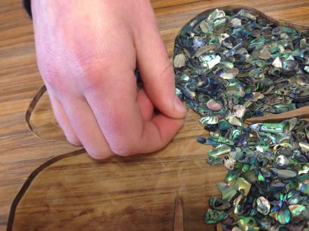 Sarah's hand placing the paua in the design