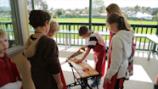 Student sawing while others observe